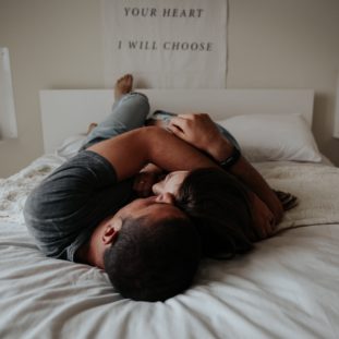 A man and woman cuddling together in bed.